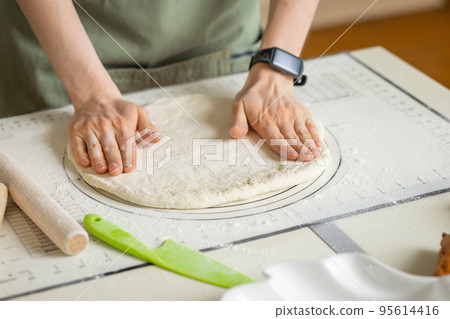 Woman hands with electronic bracelet cooking homemade pastry on silicone baking mat with markings and tips 95614416
