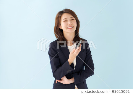 拿著智能手機藍色背景的婦女 拿著智能手機藍色背景的婦女 95615091