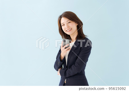 拿著智能手機藍色背景的婦女 拿著智能手機藍色背景的婦女 95615092