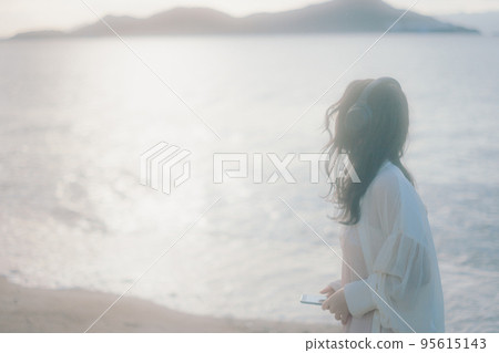 一個女人在沙灘上聽音樂的照片 95615143