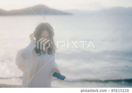 一個女人在沙灘上聽音樂的照片 一個女人在沙灘上聽音樂的照片 95615228