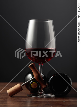 Red wine and corkscrew on a wooden table. Red wine and corkscrew on a wooden table. 95615270