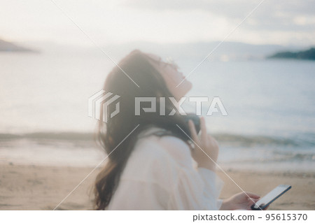 Photo of a woman listening to music on the beach Photo of a woman listening to music on the beach 95615370