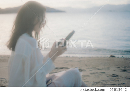 Photo of a woman listening to music on the beach Photo of a woman listening to music on the beach 95615642