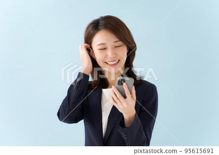 拿著智能手機藍色背景的婦女 拿著智能手機藍色背景的婦女 95615691