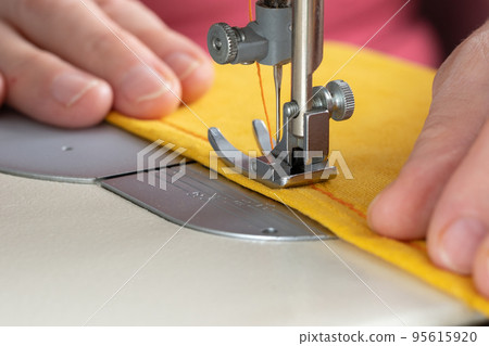 Hands of seamstress sewing with a professional machine. Concept of Factory, Home Hands of seamstress sewing with a professional machine. Concept of Factory, Home 95615920