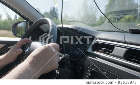 Izhevsk, Russia, August 16, 2022. Person steering wheel with one hand close up. Izhevsk, Russia, August 16, 2022. Person steering wheel with one hand close up. 95615975