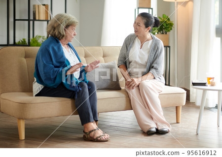 Curious senior woman listening to friend telling latest news and gossips Curious senior woman listening to friend telling latest news and gossips 95616912