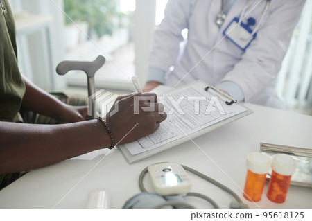 Closeup image of patient filling health insurance form in medical office Closeup image of patient filling health insurance form in medical office 95618125