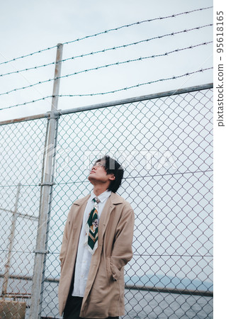man standing in front of fence man standing in front of fence 95618165