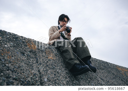 A man sitting on a breakwater 95618667