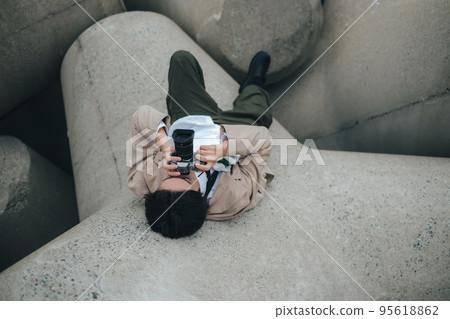 A man sitting on the breakwater and taking notes 95618862