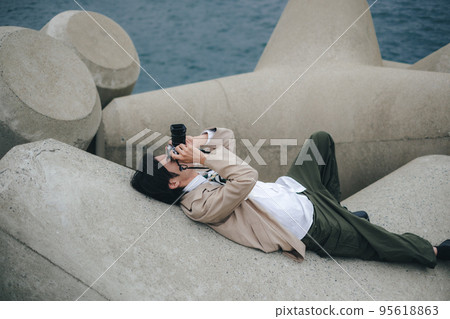 A man sitting on the breakwater and taking notes 95618863