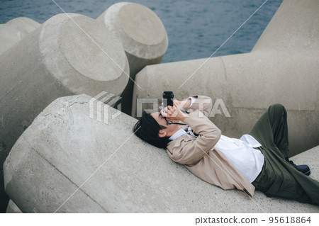 A man sitting on the breakwater and taking notes 95618864