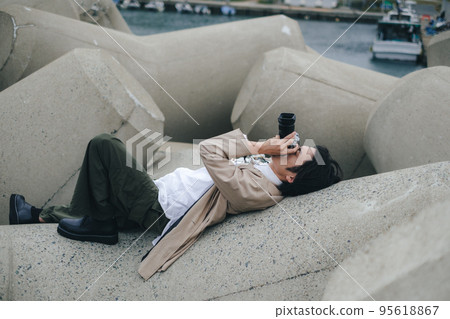 A man sitting on the breakwater and taking notes 95618867