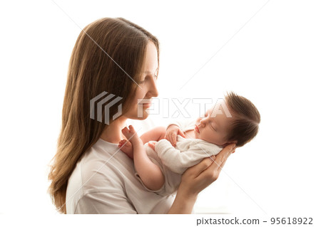 Close-up portrait of a young mother and newborn born. Mother holds in her arms, gently hugs, kisses a beautiful newborn daughter. The concept of love, happy motherhood. Photo on a white background. 95618922