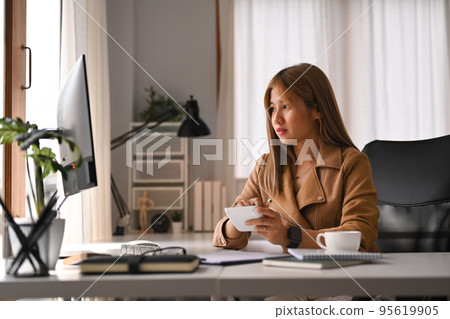 Attractive young woman looking at computer screen, analyzing financial data, working from home 95619905