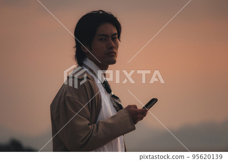 一個男人晚上在沙灘上看智能手機 一個男人晚上在沙灘上看智能手機 95620139