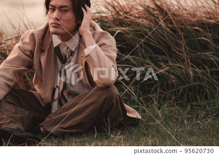 黃昏時坐在草地上的男人 黃昏時坐在草地上的男人 95620730