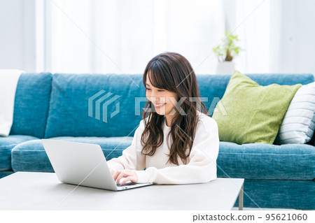 一個年輕女子在客廳裡看電腦 一個年輕女子在客廳裡看電腦 95621060