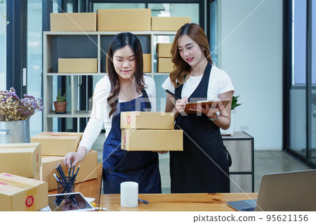 Starting small business two entrepreneur of independent Asian woman smiling using computer laptop with cheerful success of online marketing package box items and SME delivery concept. 95621156