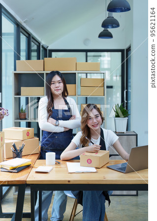Starting small business entrepreneur of independent Asian woman smiling using computer laptop with cheerful success of online marketing package box items and SME delivery concept. 95621164