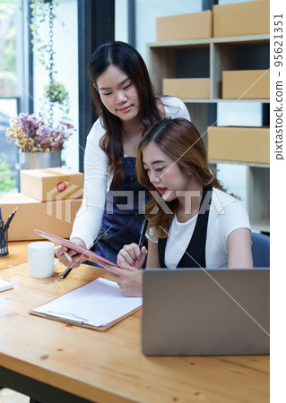 Starting small business two entrepreneur of independent Asian woman smiling using computer laptop with cheerful success of online marketing package box items and SME delivery concept. 95621351