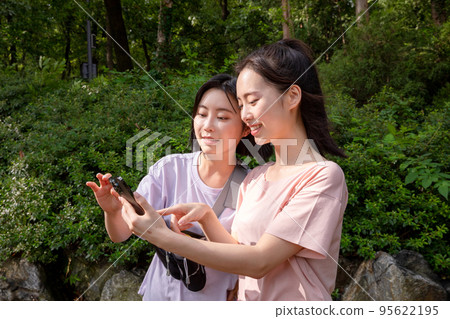 korean young women hiking and plogging_find directions using smartphone 95622195