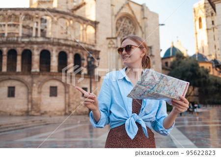 Valencia, Spain travel summer tourism holiday vacation background. Cheerful young traveller woman walking on old town holding tourist map searching direction on location map 95622823