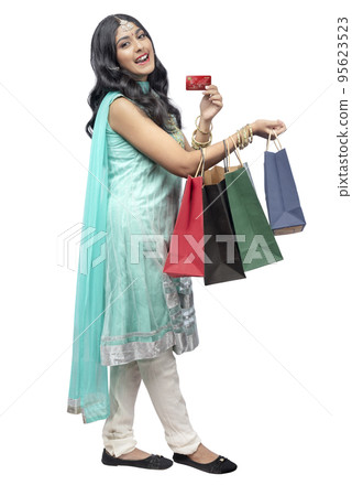 Indian woman carrying shopping bags while holding credit card Indian woman carrying shopping bags while holding credit card 95623523