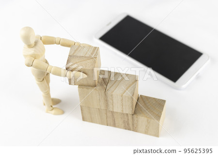 A wooden block, a drawing doll, and a smartphone. Image of work automation A wooden block, a drawing doll, and a smartphone. Image of work automation 95625395