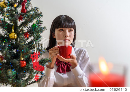 A high school girl looking forward to Christmas drinking a drink from a mug and warming up A high school girl looking forward to Christmas drinking a drink from a mug and warming up 95626540