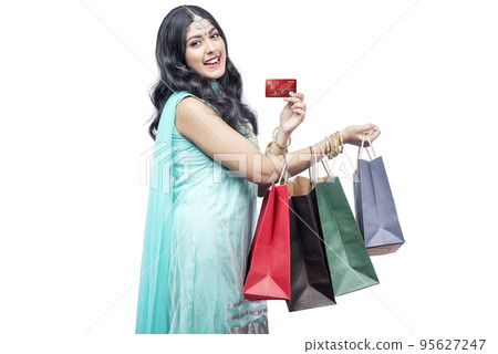 Indian woman carrying shopping bags while holding credit card Indian woman carrying shopping bags while holding credit card 95627247