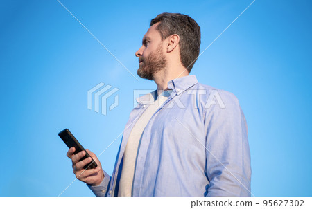 mature man chat on phone with message. man chatting on phone messaging. smartphone communication. mature man chat on phone with message. man chatting on phone messaging. smartphone communication. 95627302