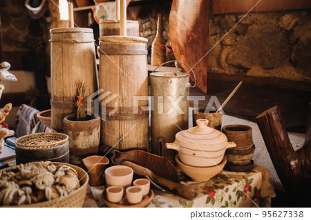 Old wooden barrels and dishes on the table in the village. Rustic antique tableware Old wooden barrels and dishes on the table in the village. Rustic antique tableware 95627338