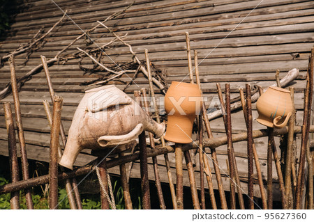 old clay pots just hang on a wicker fence. Ukrainian ethnic dishes, traditional culture of Ukraine old clay pots just hang on a wicker fence. Ukrainian ethnic dishes, traditional culture of Ukraine 95627360