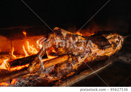 The lamb is cooked entirely on a spit on the fire. Cooking The lamb is cooked entirely on a spit on the fire. Cooking 95627536