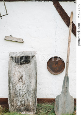 An old wooden wall of a house in the village and tools near the wall An old wooden wall of a house in the village and tools near the wall 95627729