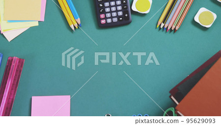 Overhead view of multicolored pencils with calculator, ruler, sticky notes and books on blue table 95629093