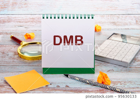 DMB text is written on a notebook sheet, next to a calculator, stickers, pencil, magnifying glass DMB text is written on a notebook sheet, next to a calculator, stickers, pencil, magnifying glass 95630133