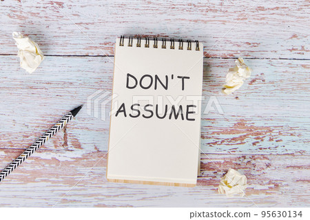 The notebook lies on the wooden floor with the text Don't Assume The notebook lies on the wooden floor with the text Don't Assume 95630134