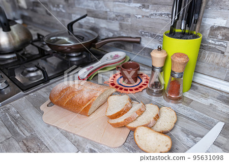 Sliced bread lies on a cutting board on kitchen table 95631098