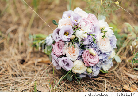 An elegant wedding bouquet of the bride lies on needles in a pine forest An elegant wedding bouquet of the bride lies on needles in a pine forest 95631117