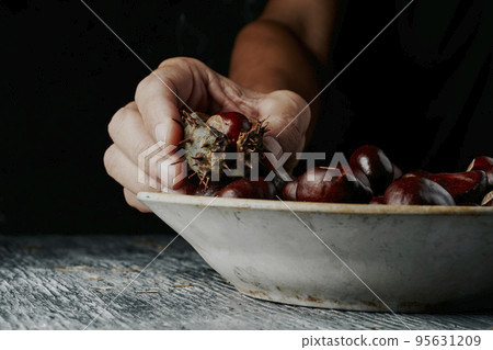 man taking a chestnut in its shell from a plate man taking a chestnut in its shell from a plate 95631209