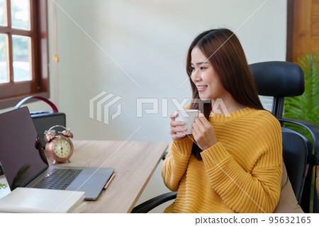 Portrait of an Asian businesswoman or business owner taking a coffee break while working in the office. 95632165