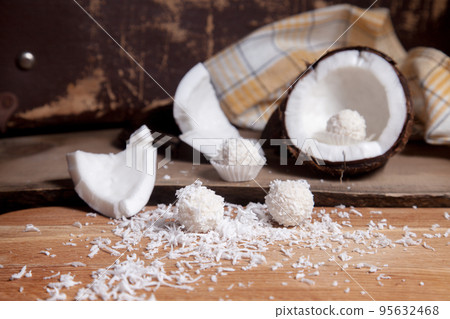 Close up of coconut with white pulp, coconut chip and white candies on wooden background.. 95632468