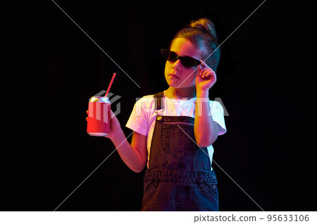 Relax mood. Charming little girl, pupil in casual style clothes isolated over dark background. Concept of children emotions, fashion, facial expressions 95633106