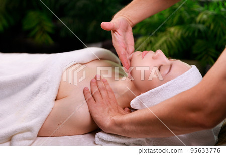 Close-up of a beautiful woman receiving a soothing head massage.  95633776