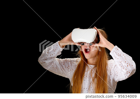 Young woman in white shirt and jeans wearing virtual helmet. Woman standing with folded hands. 95634009