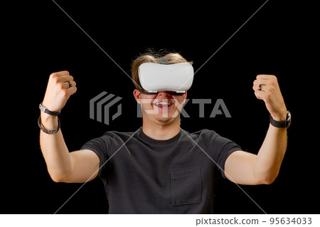 Young man wearing virtual reality VR glasses, goggles isolated on black background. Inside A Metaverse 95634033